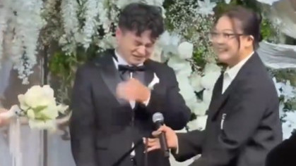 Bride gives gift on wedding stage as groom gets emotional with joy