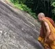 Monk climbs up steep mountain without a safety harness