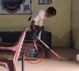 A Man Sweeping in Police Station while his legs chained to table