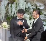 Bride gives gift on wedding stage as groom gets emotional with joy