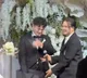 Bride gives gift on wedding stage as groom gets emotional with joy